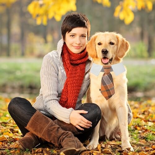 Woman sitting with a dog wearing a tie in a park during autumn.